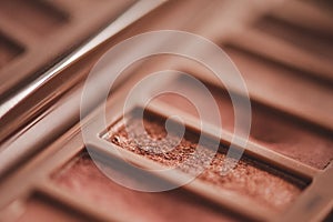 Glitter rose gold eyeshadow palette in plastic box in beige shades close up.