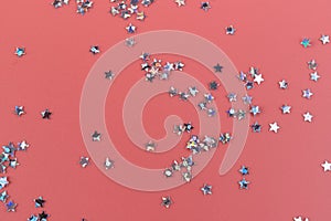 Glitter stars confetti on pink background in bright pastel colors. Festive Christmas background. Festive holiday pastel backdrop