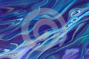 Glitter teal, purple, blue, black, and white form rolling ocean waves in this abstract acrylic pour painting for backgrounds.
