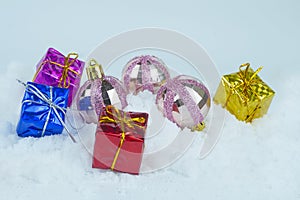 Glittered Christmas baubles with colorful presents with metallic strings