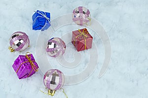 Glittered Christmas baubles with colorful presents with metallic strings