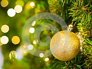 Glittering Baubles with Glowing Sparkling Gold defocused Light bokeh Illumination background with decorated Christmas Tree.