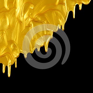 Glittering shiny metallic gold paint flowing and dripping downward. Isolated on black