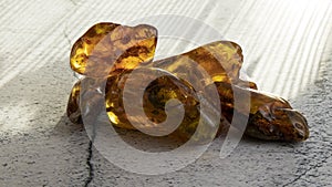 Glittering transparent orange Baltic amber stones  on a gray surface.