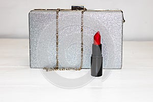 Glittery silver clutch bag with red lipstick isolated on white background with copy space