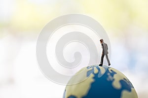 Global Business and Planning Concept. Close up of businessman miniature figure people walking on world mini ball with copy space