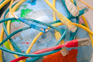 Global Communication Technology Concept. High-speed cable. Fiber optic patch cord is close-up on a background of the globe.