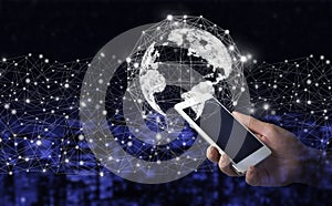 Global connection concept. Hand hold white smartphone with digital hologram world, earth, map, globe sign on city dark blurred