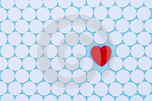 Global healthcare concept. Little red heart. Background of white pills macro with a red heart lying on