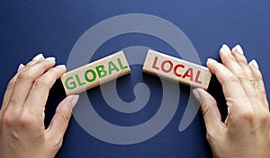 Global and Local symbol. Concept word Global and Local on wooden blocks. Businessman hand. Beautiful deep blue background.