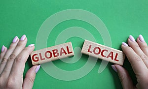 Global and Local symbol. Concept word Global and Local on wooden blocks. Businessman hand. Beautiful green background. Business