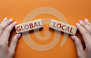 Global and Local symbol. Concept word Global and Local on wooden blocks. Businessman hand. Beautiful orange background. Business