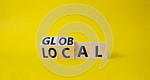 Global and Local symbol. Turned wooden cubes with words Global and Local. Beautiful yellow background. Business and Global and