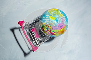 Global Market. World globe in shopping trolley on Grey background