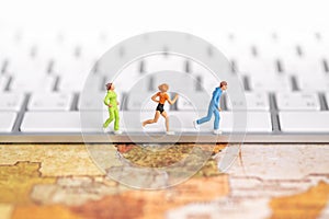 Global sport and technology concept. Close up of group of runner miniature figures running on computer keyboard on world map