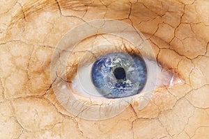 Global warming concept. Close up image of woman cracked textured face with iris earth. Creative composite of macro Eye
