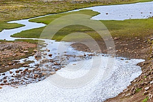 Global warming melting snow in to flow river - green grass