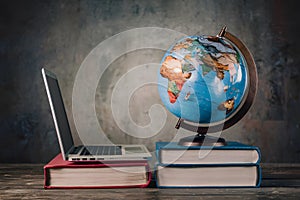 Globalization business or education concept with globe and laptop on books pile