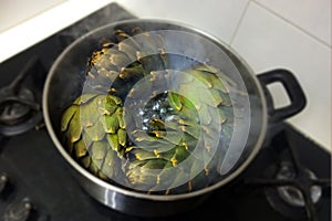 Globe artichokes being cooked in hot water