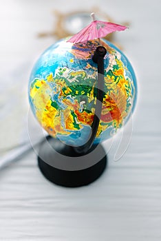 Globe with beach umbrellas on a wooden white background.