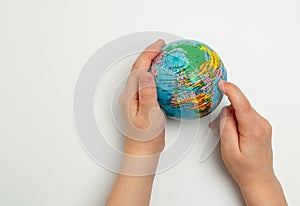 The globe in children& x27;s hands. Child& x27;s finger indicating a place on the globe. Children& x27;s education concept