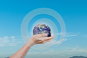 Globe, earth in human hands over blue sky background