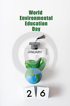 Globe with green leaves, graduated cap and 26 january. World Environmental Education Day text