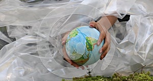 globe in hands plastic film green forest, Pollution of the environment.