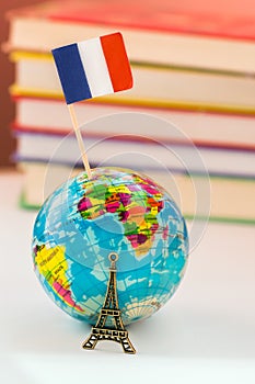 Globe icon the Eiffel Tower on the background of books and textbooks. Learn French. French language courses, practice in France.