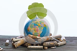 Globe with inscriptions in cyrillic, above it is a green sprout. Around him are spent batteries, covered with corrosion. World