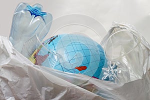 The globe lies in a bag with plastic trash. Planet earth is surrounded by plastic bottles, bags, glasses. The concept of