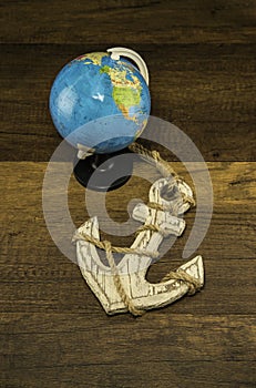 Globe model with old white anchor on wooden background