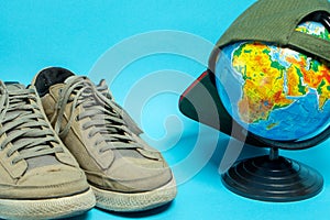 Globe and old worn sneakers in gray on a blue background. Geographical names on the globe in Russian