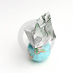 Globe and a paper boat out of a dollar bill