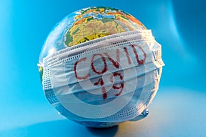 Globe of planet dressed a medical mask with text Covid -19 worldwide epidemic. Coronavirus planet pandemic concept