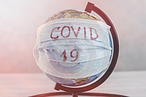 Globe of planet dressed a medical mask with text Covid -19 worldwide epidemic. Coronavirus planet pandemic concept