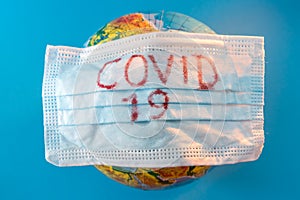 Globe of planet dressed a medical mask with text Covid -19 worldwide epidemic. Coronavirus planet pandemic concept