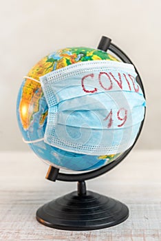 Globe of planet dressed a medical mask with text Covid -19 worldwide epidemic. Coronavirus planet pandemic concept