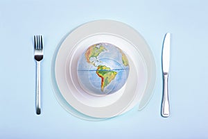 Globe on a plate for food on a blue background. Power, economy, politics, globalism, hunger, poverty and world food concept photo