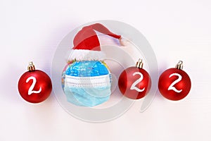 Globe in protective medical face mask on white background. Planet Earth in santa hat. New year health care concept
