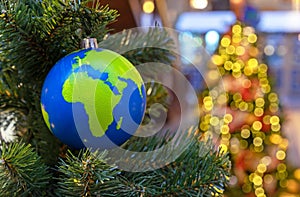 Globe-shaped Christmas ball with countries and continents on the Christmas tree.