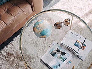 Globe, Sunglasses, and Travel Magazines on Glass Table