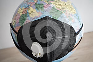 Globe wear black medical face mask on wooden table white wall background. Global novel coronavirus Covid-19 outbreak pandemic