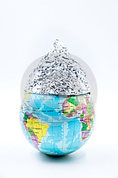 Globe wearing a tin foil hat, isolated on white background, concept conspiracy theory photo