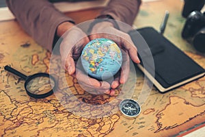 Globe, whole world in hands and compass, magnifying glass and book on route map on the table. Travel , Adventure and Discovery