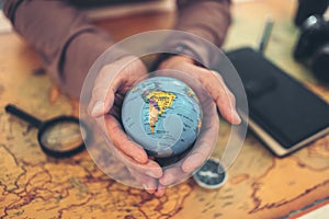 Globe, whole world in hands and compass, magnifying glass and book on route map on the table. Travel , Adventure and Discovery