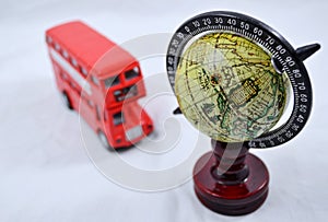 Globe with wooden stand and with double decker bus model on white - traveling