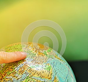 A globe world map with an index finger on it