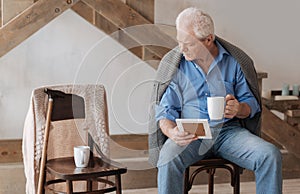 Gloomy aged man looking at the chair near him