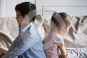 Gloomy children sitting on couch at home